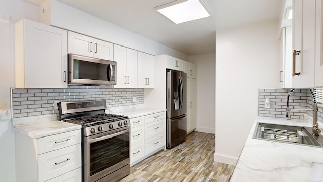 11427 Colonial Woods Dr, Clio, MI 48420 - kitchen featuring stainless steel appliances, decorative backsplash, light stone countertops, light wood finished floors, and white cabinets