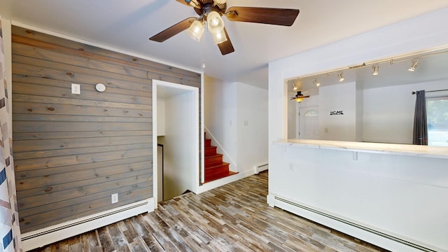 11427 Colonial Woods Dr, Clio, MI 48420 - unfurnished room featuring a baseboard radiator, ceiling fan, stairway, and wood finished floors