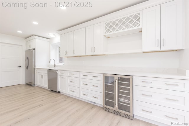 3145 Point Of The Woods Dr, West Bloomfield, MI 48324 - kitchen featuring beverage cooler, stainless steel appliances, light countertops, light wood-style floors, and white cabinets