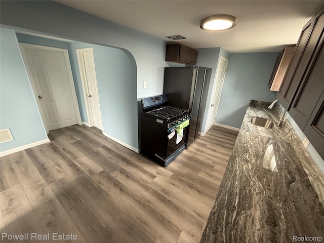 2326 Silver Cir, Pontiac, MI 48328 - kitchen featuring gas stove, light wood-type flooring, arched walkways, and dark stone counters