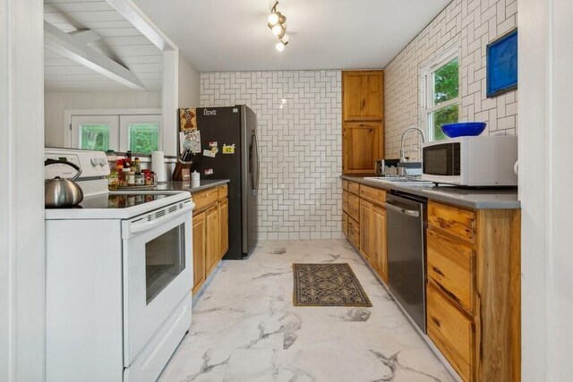 13176 Red Arrow Hwy, Sawyer, MI 49125 - kitchen featuring stainless steel appliances, brown cabinetry, brick wall, light marble finish flooring, and dark countertops