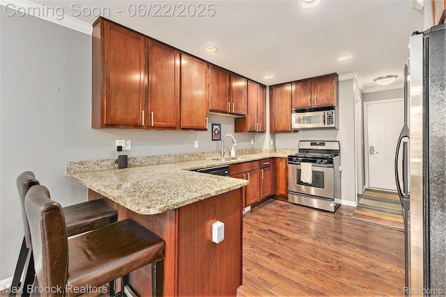 417 James Cir, Royal Oak, MI 48067 - kitchen with appliances with stainless steel finishes, crown molding, a peninsula, light stone countertops, and wood finished floors