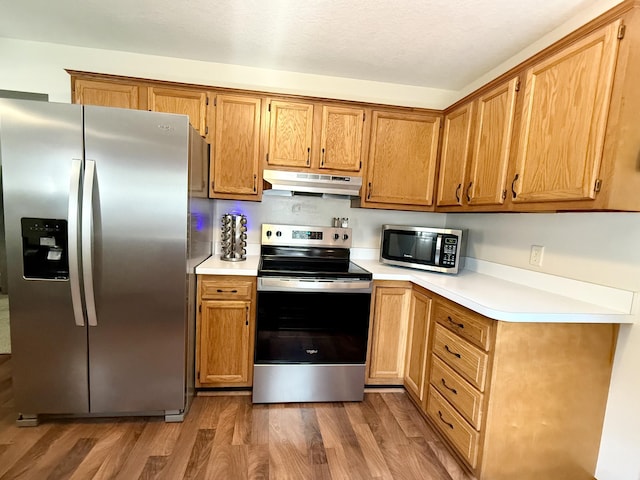 8021 Mclain Ave, Lambertville, MI 48144 - kitchen with appliances with stainless steel finishes, under cabinet range hood, wood finished floors, and light countertops