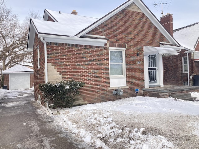 11751 Engleside St, Detroit, MI 48205 - view of snowy exterior with a chimney, brick siding, an outbuilding, and a garage