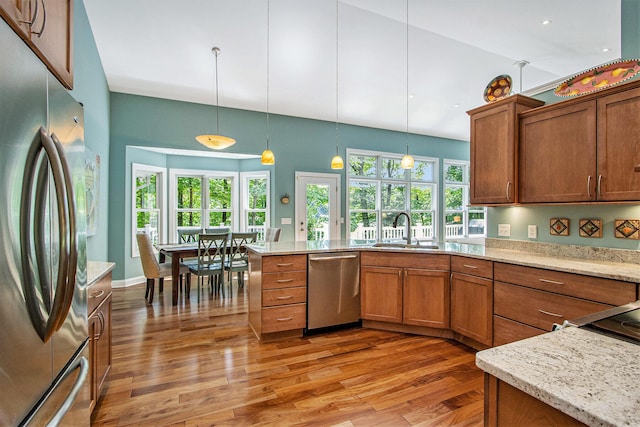 3314 Westview Ct, Allegan, MI 49010 - kitchen with stainless steel appliances, brown cabinets, light wood-style flooring, and hanging light fixtures