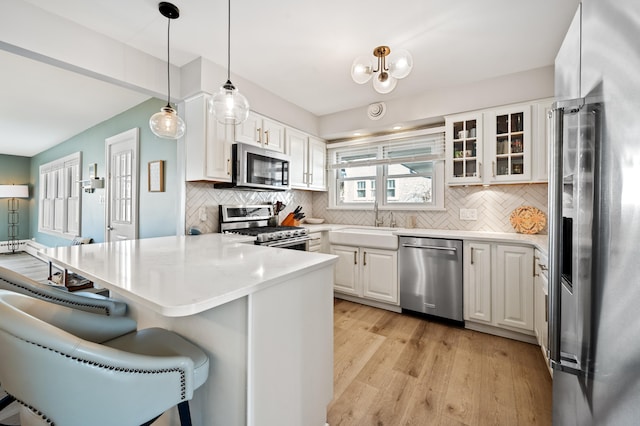 1908 Niles Ave, Saint Joseph, MI 49085 - kitchen featuring stainless steel appliances, a peninsula, a kitchen bar, and white cabinetry