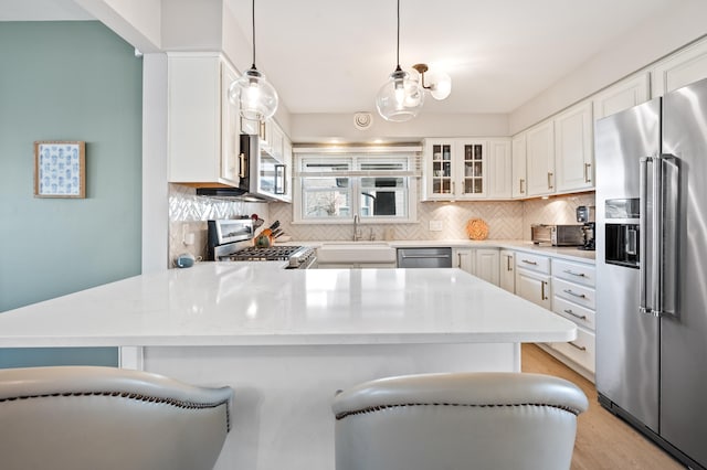 1908 Niles Ave, Saint Joseph, MI 49085 - kitchen featuring stainless steel appliances, tasteful backsplash, a peninsula, white cabinetry, and glass insert cabinets