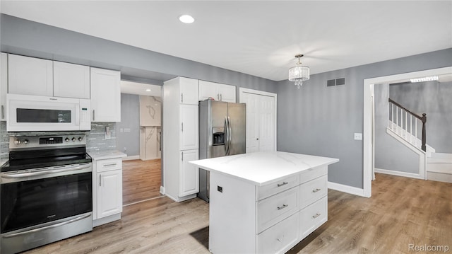 6596 Corral Ct, West Bloomfield, MI 48324 - kitchen with appliances with stainless steel finishes, white cabinetry, light countertops, backsplash, and light wood-type flooring