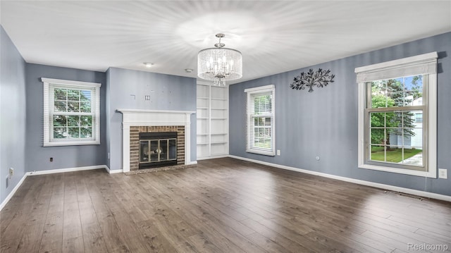 6596 Corral Ct, West Bloomfield, MI 48324 - unfurnished living room with plenty of natural light, a chandelier, dark wood finished floors, and a brick fireplace