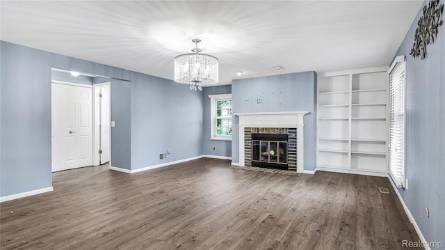 6596 Corral Ct, West Bloomfield, MI 48324 - unfurnished living room with a chandelier, dark wood-type flooring, a brick fireplace, and built in shelves