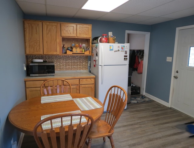 1513 Joy Ave, Jackson, MI 49203 - kitchen featuring freestanding refrigerator, stainless steel microwave, wood finished floors, light countertops, and a paneled ceiling