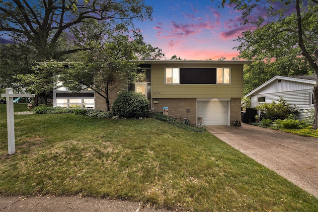 2975 Princeton Ct, Muskegon, MI 49441 - split level home with brick siding, an attached garage, concrete driveway, and a yard