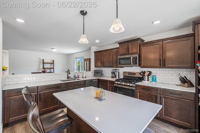 1013 Lancaster St, Lapeer, MI 48446 - kitchen with stainless steel appliances, light countertops, light wood-style flooring, dark brown cabinetry, and decorative backsplash