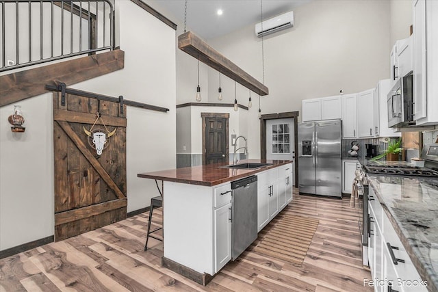 2539 Daisy Ln, Middleville, MI 49333 - kitchen featuring appliances with stainless steel finishes, a towering ceiling, light wood-style floors, a kitchen breakfast bar, and a wall unit AC