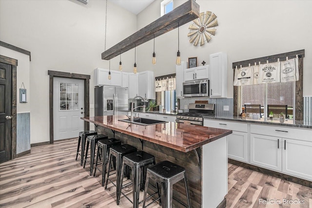 2539 Daisy Ln, Middleville, MI 49333 - kitchen featuring appliances with stainless steel finishes, a towering ceiling, light wood-type flooring, a breakfast bar area, and white cabinets