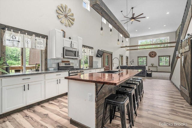 2539 Daisy Ln, Middleville, MI 49333 - kitchen featuring appliances with stainless steel finishes, a high ceiling, wood counters, light wood finished floors, and a kitchen island with sink