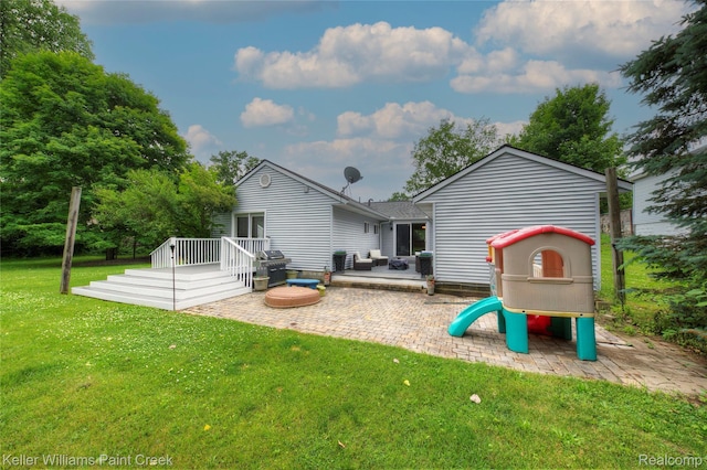1320 W Drahner Rd, Oxford, MI 48371 - rear view of house featuring a playground, a lawn, a wooden deck, and a patio
