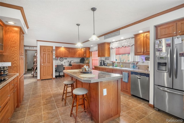 3933 Benjamin Way, Monroe, MI 48161 - kitchen with stainless steel appliances, crown molding, a breakfast bar, a kitchen island, and brown cabinetry