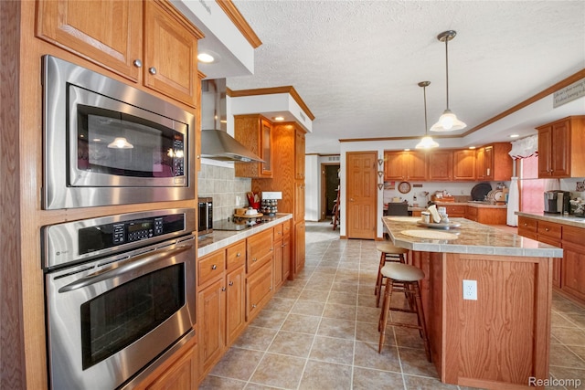 3933 Benjamin Way, Monroe, MI 48161 - kitchen with stainless steel appliances, wall chimney range hood, light countertops, tasteful backsplash, and brown cabinets