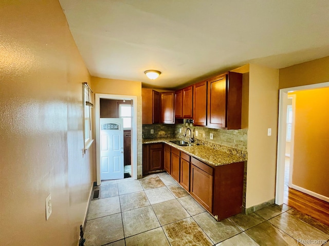 20817 Atlantic Ave, Warren, MI 48091 - kitchen featuring tasteful backsplash, light stone counters, brown cabinetry, and light tile patterned flooring