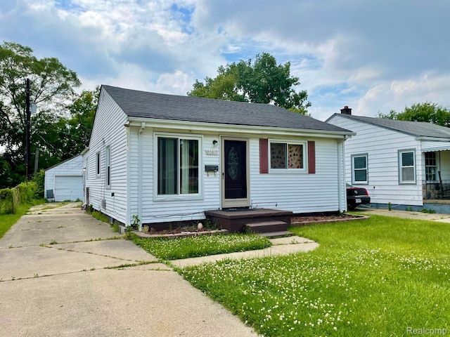 20817 Atlantic Ave, Warren, MI 48091 - view of front facade featuring a front yard, an outbuilding, a detached garage, and roof with shingles