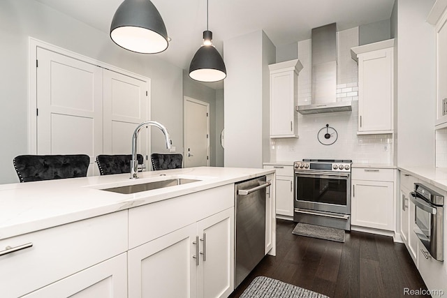 1021 S Washington Ave Unit G, Royal Oak, MI 48067 - kitchen featuring appliances with stainless steel finishes, wall chimney range hood, dark wood-style floors, backsplash, and white cabinetry