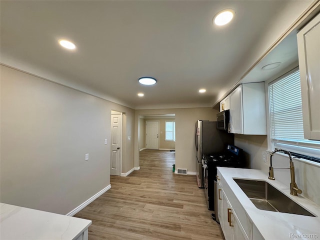 14276 Hobart Ave, Warren, MI 48089 - kitchen featuring gas range, stainless steel microwave, white cabinetry, light wood finished floors, and recessed lighting