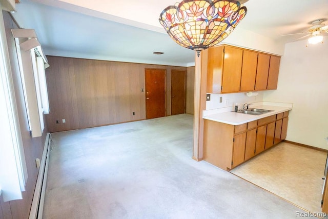 3400 Elizabeth Dr Unit 4, Trenton, MI 48183 - kitchen with a baseboard radiator, light countertops, ceiling fan, brown cabinets, and wood walls
