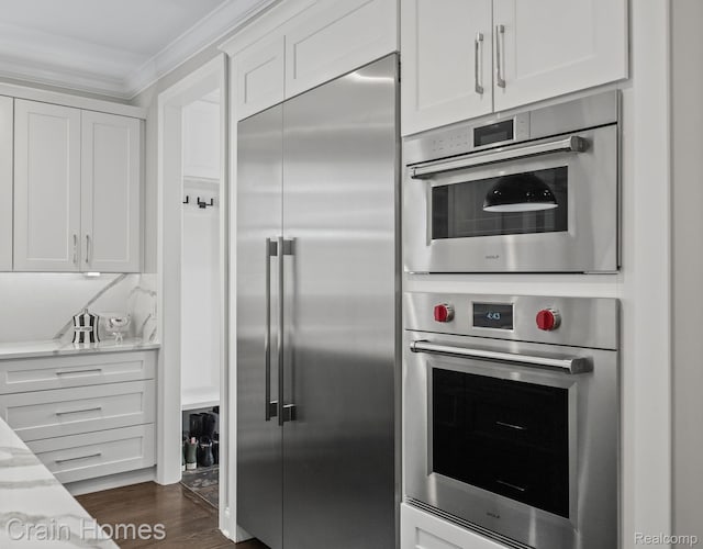 1790 Washington Blvd, Birmingham, MI 48009 - kitchen featuring stainless steel appliances, white cabinets, crown molding, light stone countertops, and dark wood-style flooring