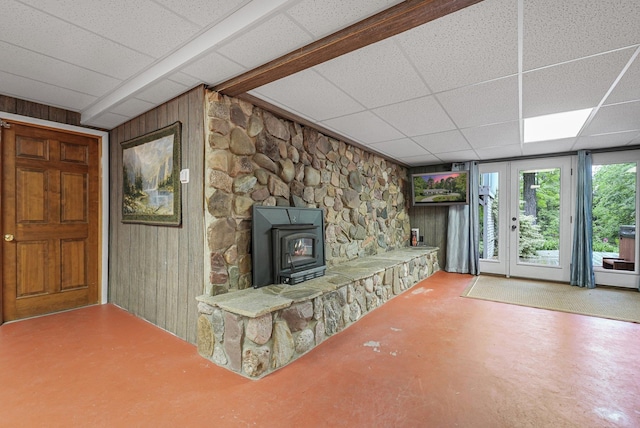 4301B W Sanborn Rd, Lake City, MI 49651 - unfurnished living room with a wood stove, wood walls, a drop ceiling, and finished concrete floors