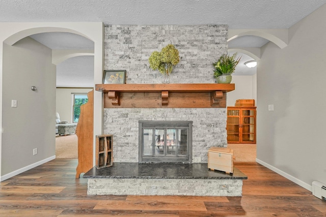 4301B W Sanborn Rd, Lake City, MI 49651 - detailed view of arched walkways, a multi sided fireplace, wood finished floors, a textured ceiling, and baseboard heating