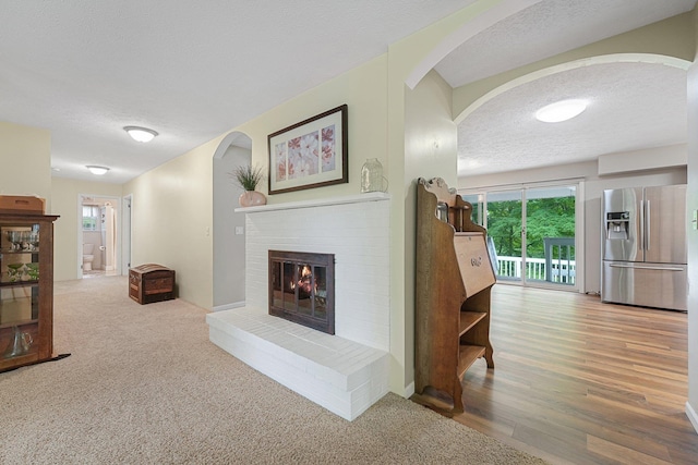 4301B W Sanborn Rd, Lake City, MI 49651 - living room featuring arched walkways, a textured ceiling, healthy amount of natural light, and a fireplace