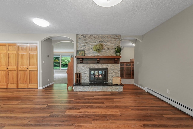 4301B W Sanborn Rd, Lake City, MI 49651 - unfurnished living room with a baseboard radiator, wood finished floors, arched walkways, a textured ceiling, and a stone fireplace