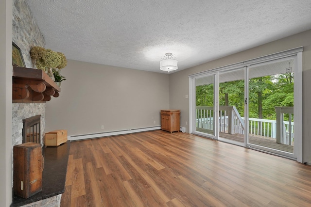 4301B W Sanborn Rd, Lake City, MI 49651 - unfurnished living room featuring a baseboard radiator, healthy amount of natural light, wood finished floors, and a textured ceiling