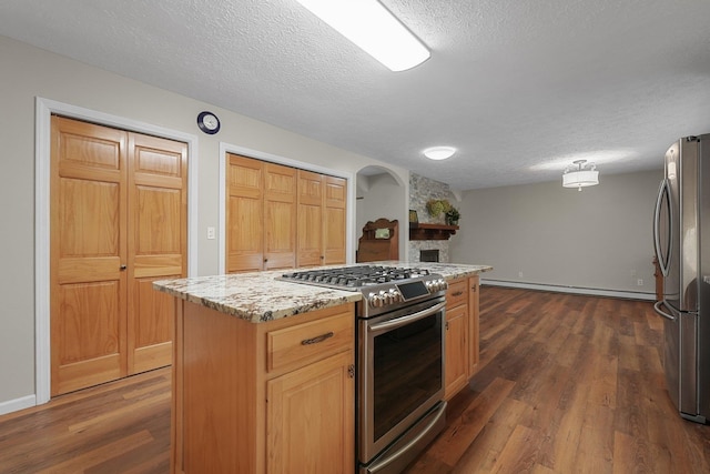 4301B W Sanborn Rd, Lake City, MI 49651 - kitchen featuring appliances with stainless steel finishes, a baseboard heating unit, a textured ceiling, dark wood-style flooring, and a fireplace