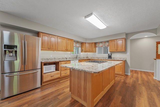 4301B W Sanborn Rd, Lake City, MI 49651 - kitchen with stainless steel appliances, a textured ceiling, wood finished floors, a kitchen island, and light stone countertops