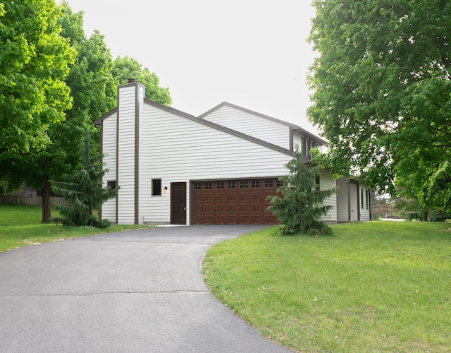 5825 Saddle Club Dr, Kalamazoo, MI 49009 - view of side of property with driveway, a chimney, a lawn, and an attached garage