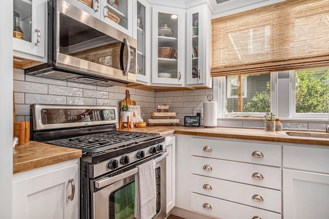 832 Clancy Ave NE, Grand Rapids, MI 49503 - kitchen featuring stainless steel appliances, butcher block countertops, backsplash, and white cabinetry