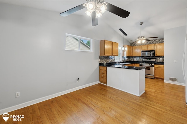 11419 Autumn Breeze Trl, Clio, MI 48420 - kitchen with stainless steel appliances, ceiling fan, a peninsula, vaulted ceiling, and decorative backsplash