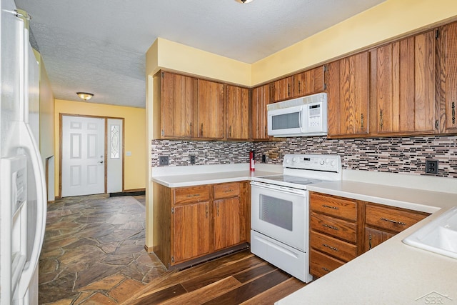 4918 Frontier Ln, Saginaw, MI 48603 - kitchen with white appliances, brown cabinetry, light countertops, decorative backsplash, and a textured ceiling