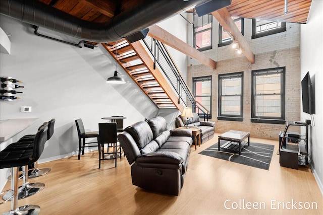 600 Monroe Ave NW Unit 409, Grand Rapids, MI 49503 - living room with brick wall, a towering ceiling, wood finished floors, stairs, and plenty of natural light