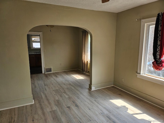 1102 W Atherton Rd W, Flint, MI 48507 - unfurnished room featuring arched walkways, wood finished floors, plenty of natural light, and a textured ceiling