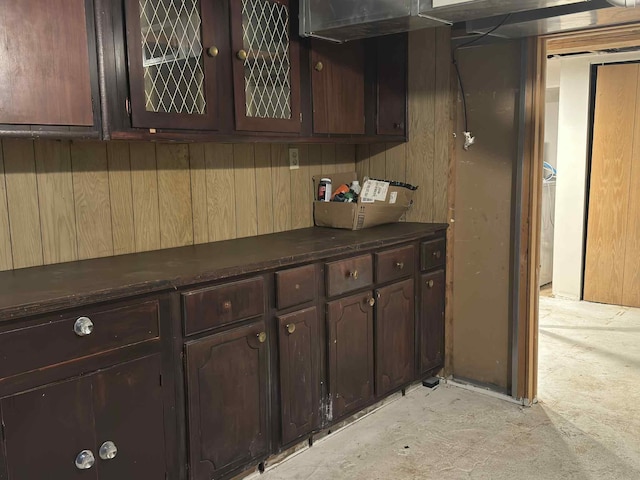 57993 Oak Park Rd, Three Rivers, MI 49093 - kitchen featuring dark countertops, dark brown cabinets, glass insert cabinets, wood walls, and concrete flooring