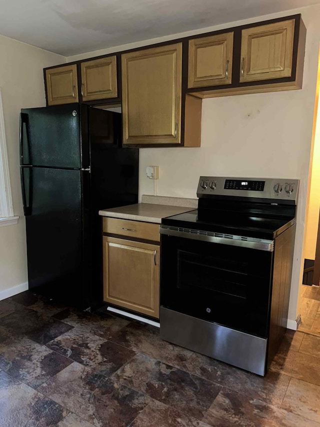 57993 Oak Park Rd, Three Rivers, MI 49093 - kitchen featuring stainless steel range with electric cooktop, freestanding refrigerator, light countertops, and dark stone finish flooring