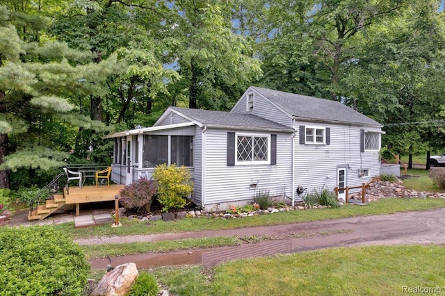 4155 Mill Lake Rd, Lake Orion, MI 48360 - view of side of property featuring a wooden deck, a sunroom, view of scattered trees, and a shingled roof