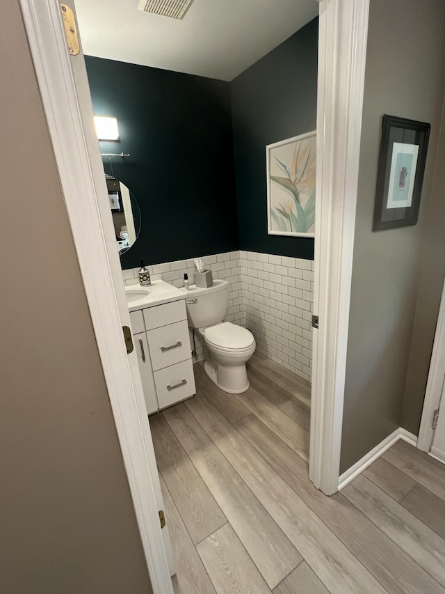 5437 Grand River Dr NE, Grand Rapids, MI 49525 - half bathroom with tile walls, wood finished floors, vanity, and a wainscoted wall