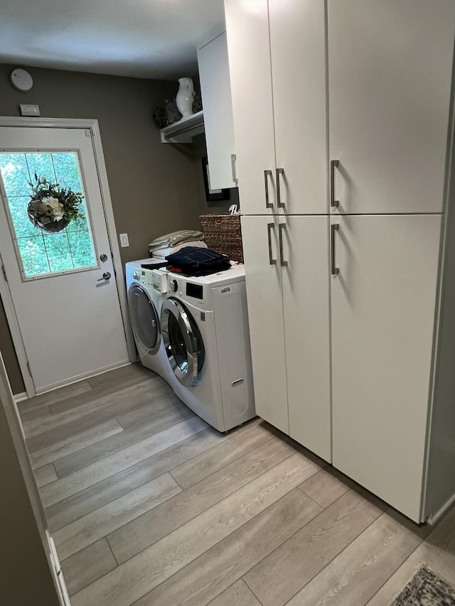 5437 Grand River Dr NE, Grand Rapids, MI 49525 - laundry area with cabinet space, light wood-style floors, and washer and clothes dryer