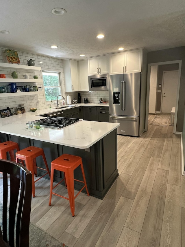5437 Grand River Dr NE, Grand Rapids, MI 49525 - kitchen featuring appliances with stainless steel finishes, light wood-style floors, a kitchen bar, tasteful backsplash, and a peninsula