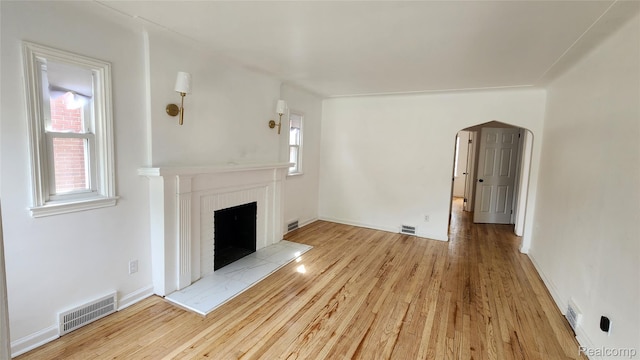 10947 Roxbury St, Detroit, MI 48224 - unfurnished living room with wood finished floors, arched walkways, and a fireplace