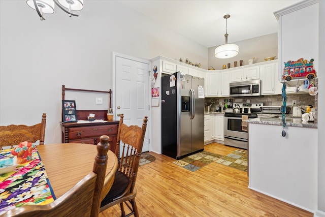 9422 Timber Ridge Dr, Grand Blanc, MI 48439 - kitchen featuring stainless steel appliances, white cabinets, light wood-style flooring, decorative light fixtures, and backsplash